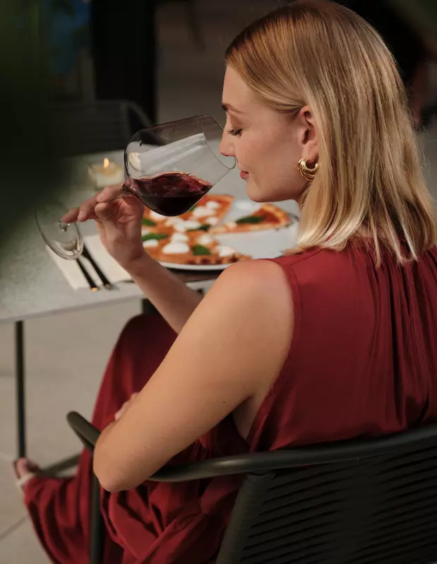 Frau mit Rotwein und Pizza am Abend in der Pizzeria