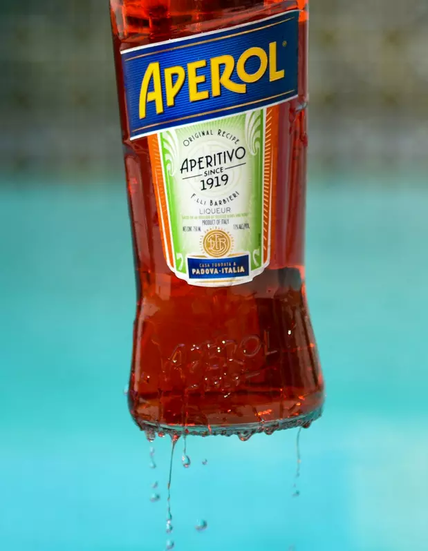Aperol-Flasche vor dem türkisblauen Pool