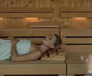 Frau entspannt auf der Holzbank in der Sauna