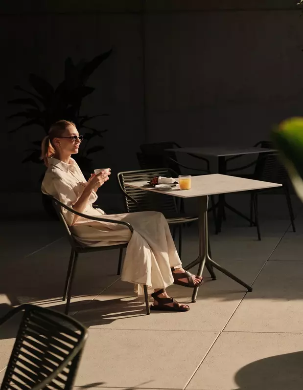 Frau mit Kaffee auf der schattigen Terrasse der Bar