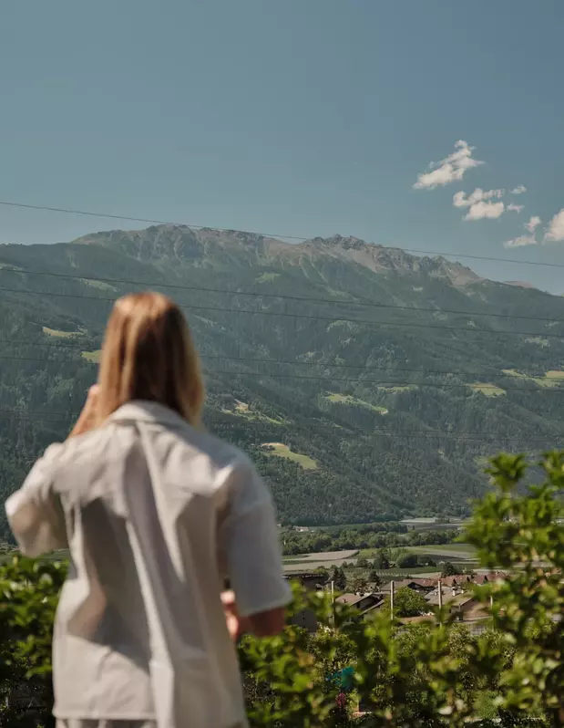 Frau blickt vom Stellplatz auf das Bergpanorama über dem Vinschgau